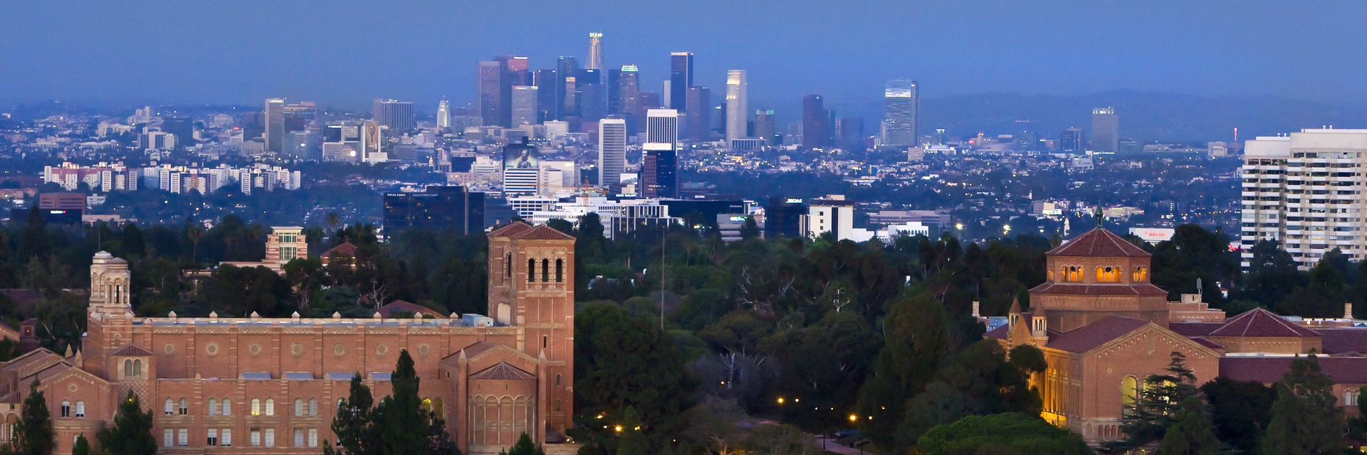 Royce Hall and Powell Library at dusk with the downtown Los Angeles skyline beyond